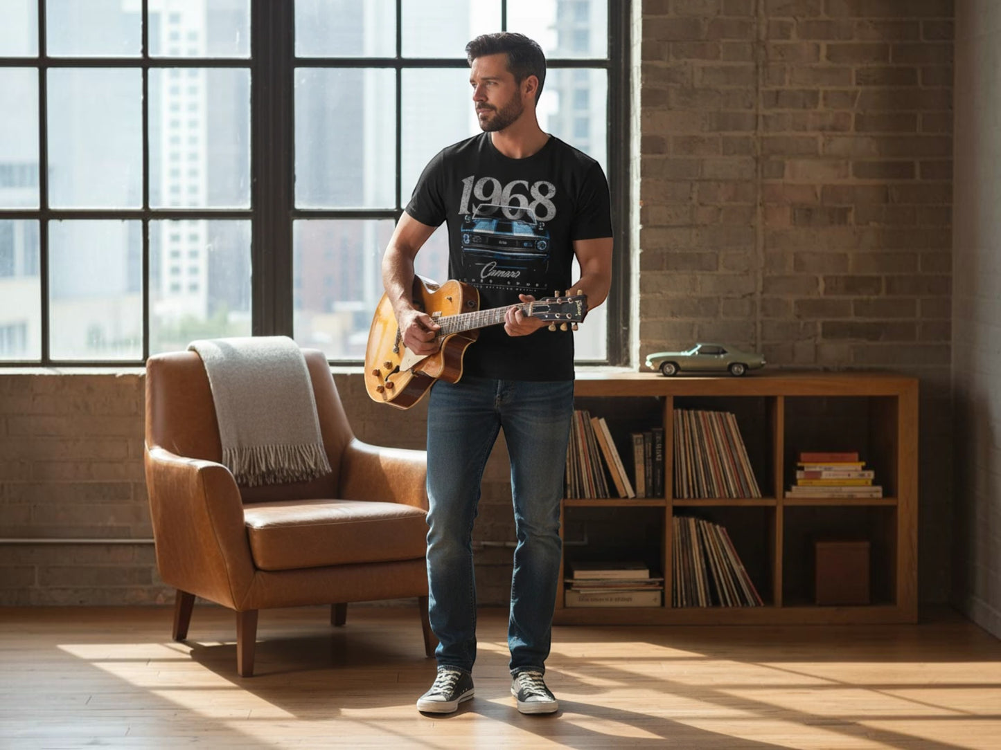 T-Top Vibes 1968 Chevrolet Camaro black t-shirt worn by a man playing an acoustic guitar in a loft setting.