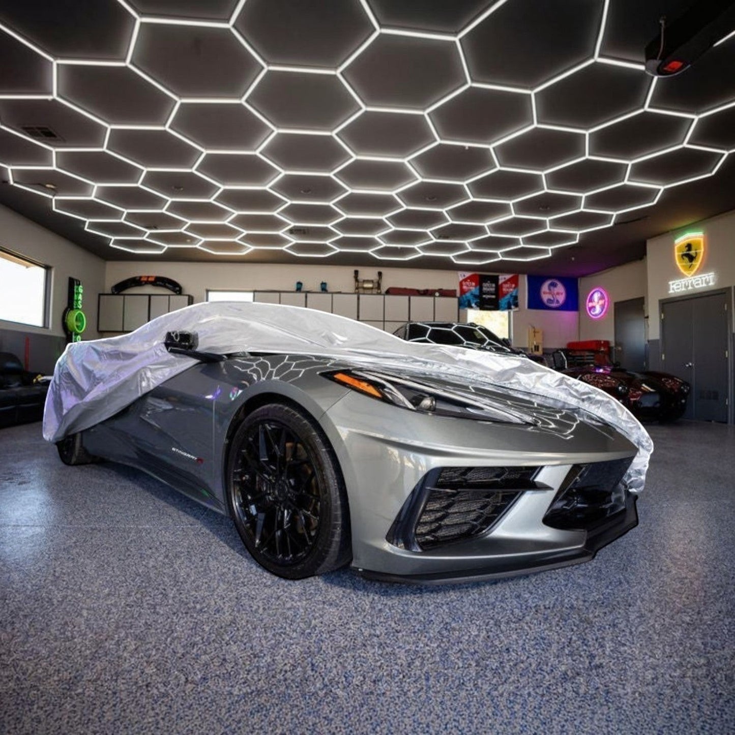 T-Top Vibes Platinum Shield outdoor car cover on a silver C8 Corvette in a modern garage with hexagonal ceiling lights