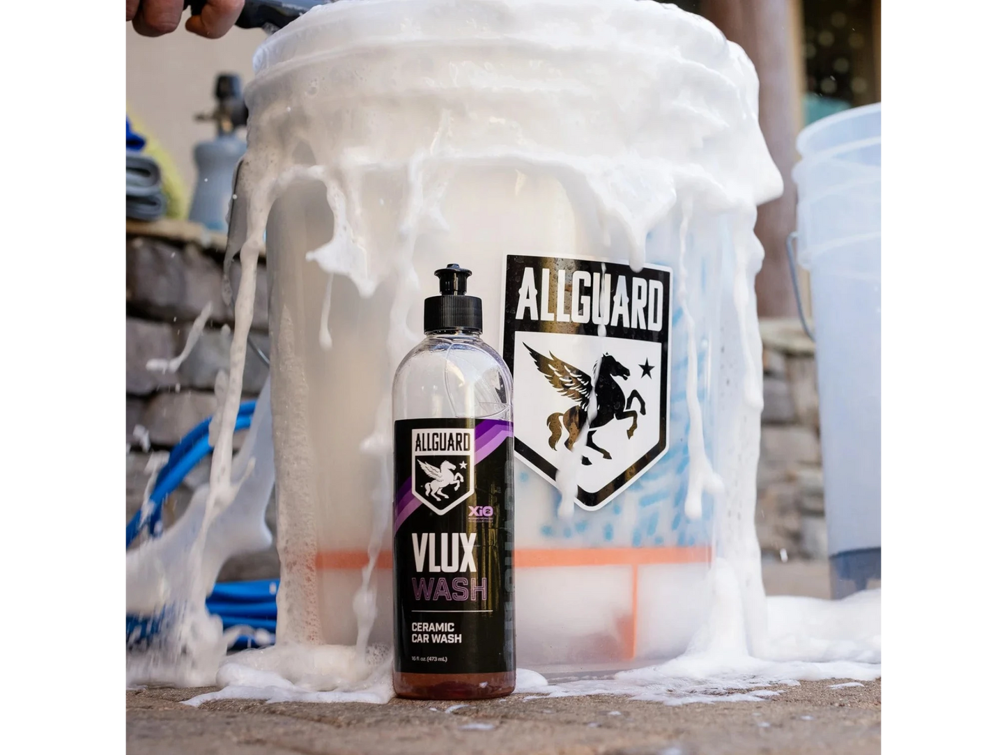 T-Top Vibes AllGuard VLUX ceramic car wash bottle covered in thick white soap suds next to a branded detailing bucket
