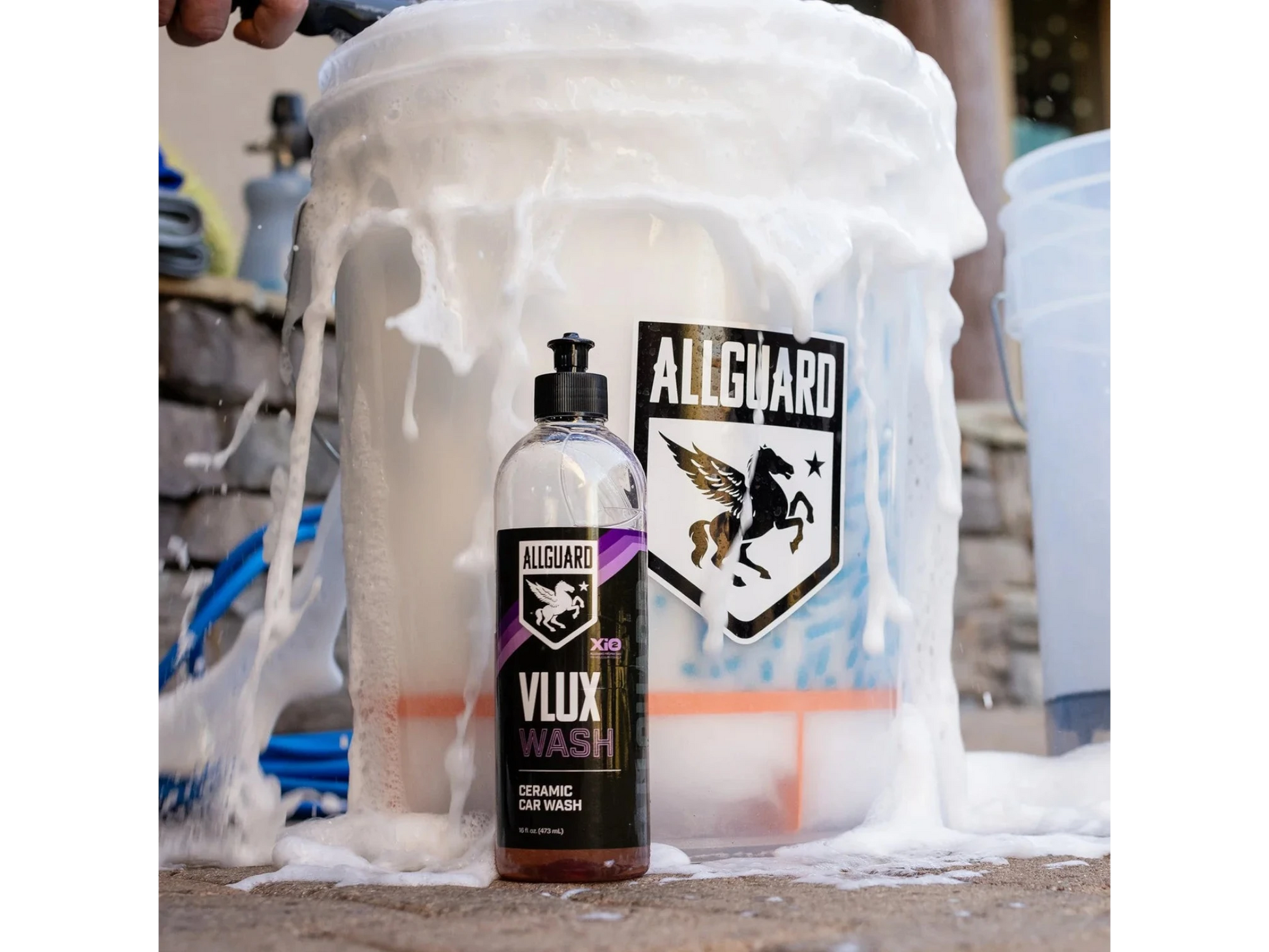 T-Top Vibes AllGuard VLUX ceramic car wash bottle covered in thick white soap suds next to a branded detailing bucket