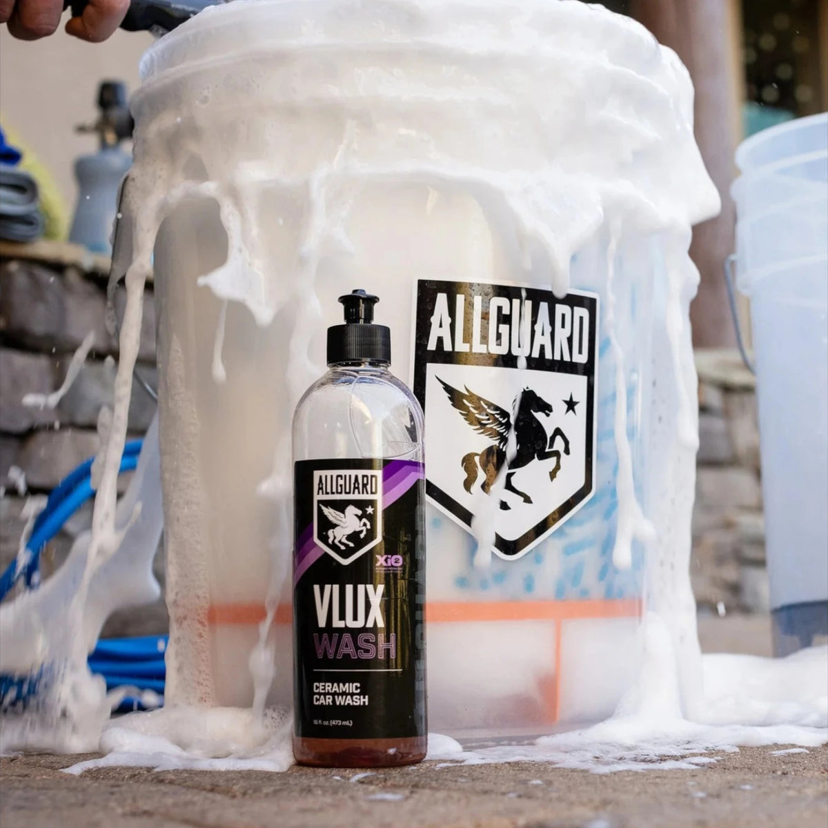 T-Top Vibes AllGuard VLUX ceramic car wash bottle covered in thick white soap suds next to a branded detailing bucket