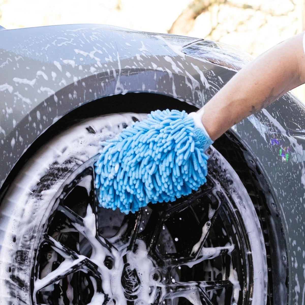 T-Top Vibes blue chenille microfiber car wash mitt cleaning a soapy vehicle wheel with an elastic wrist cuff