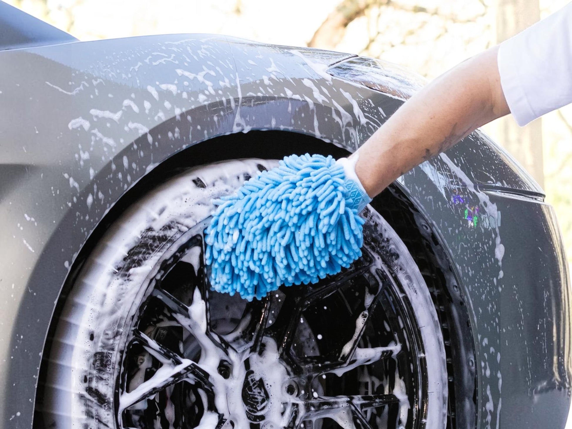 T-Top Vibes blue chenille microfiber car wash mitt cleaning a soapy black car wheel with an elastic wrist cuff