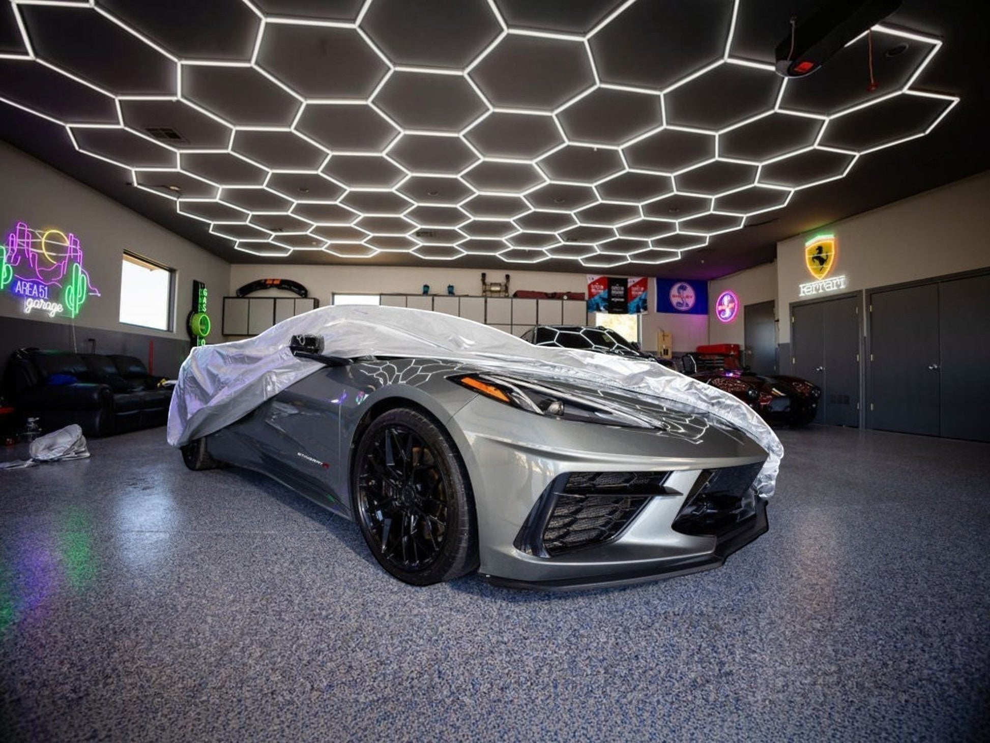 T-Top Vibes Platinum Shield outdoor car cover on a silver C8 Corvette in a modern garage with hexagonal ceiling lights
