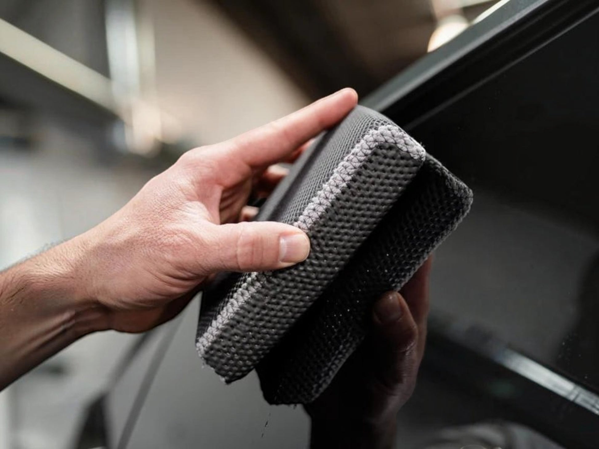 T-Top Vibes AllGuard 2-in-1 clay scrubber and bug removal pad being held against a car window for detailing