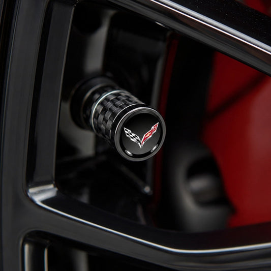 T-Top Vibes Corvette C7 carbon fiber valve stem cap with crossed-flags emblem installed on a black car wheel