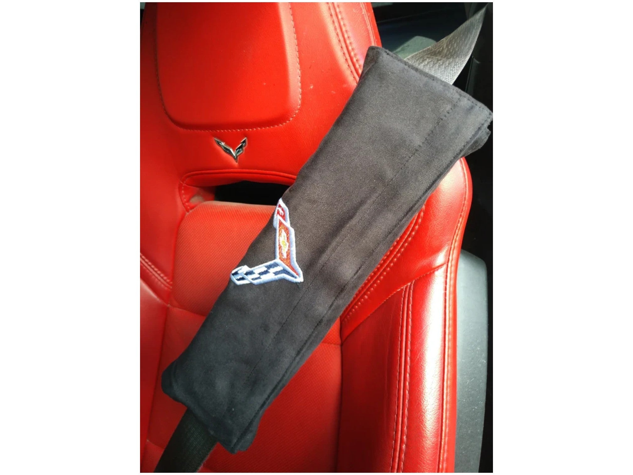 T-Top Vibes black Seat Armour seat belt cushion with embroidered C8 Corvette Crossed Flags logo on a red leather seat