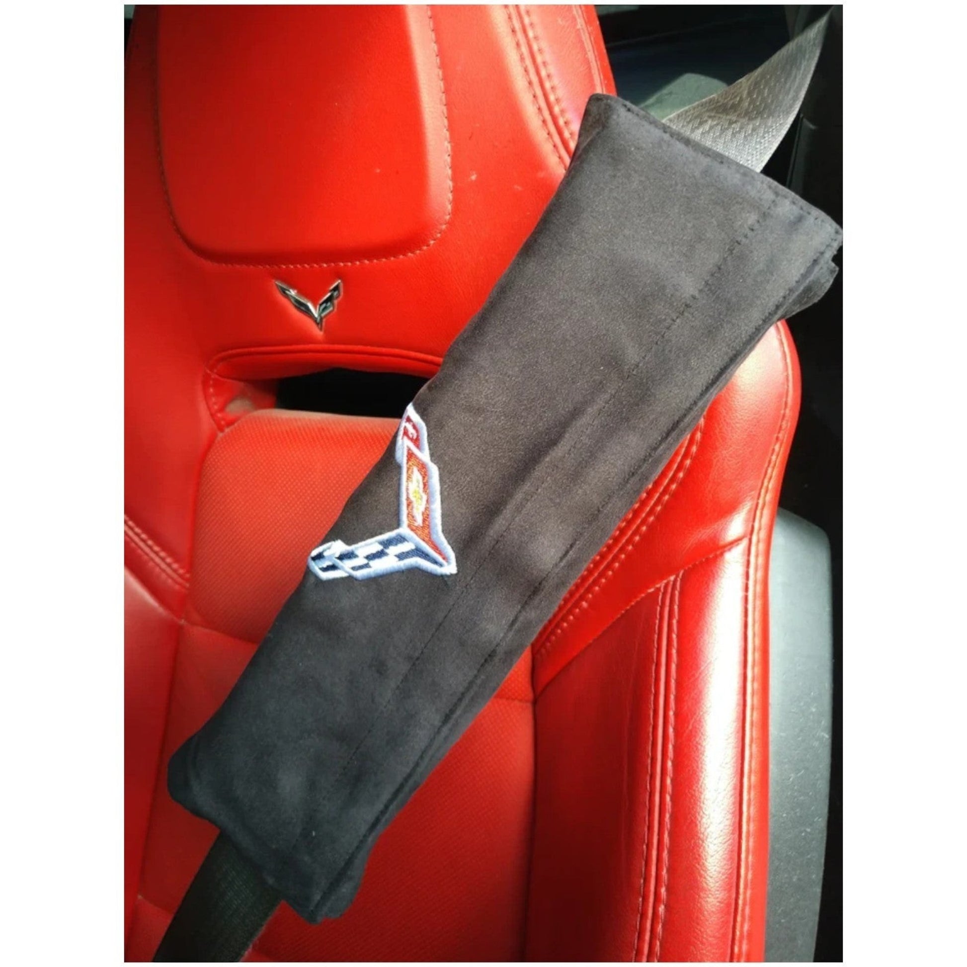T-Top Vibes black Seat Armour seat belt cushion with embroidered C8 Corvette Crossed Flags logo on a red leather seat