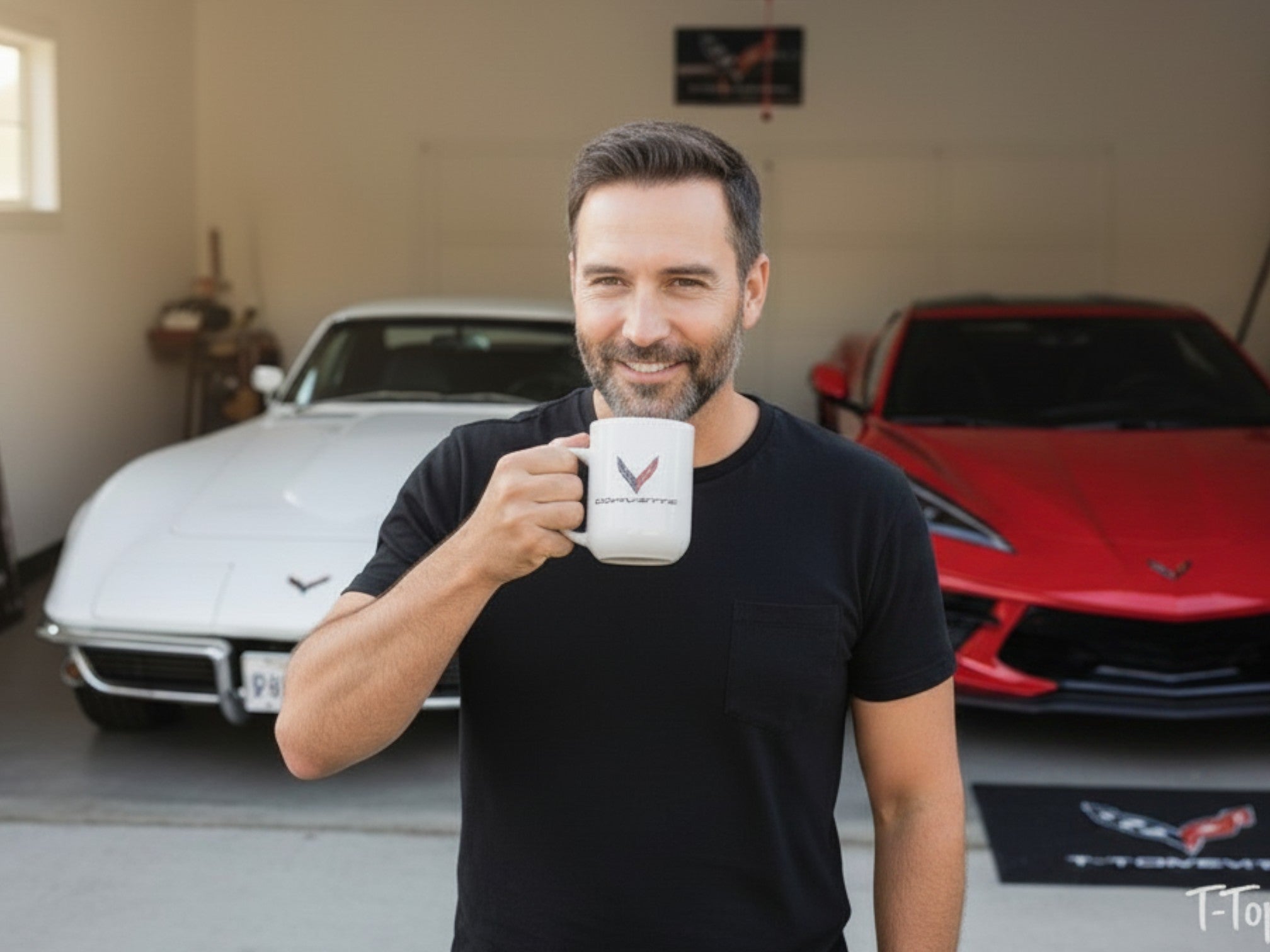 Man holding a T-Top Vibes Corvette ceramic mug in a garage with white and red sports cars in the background
