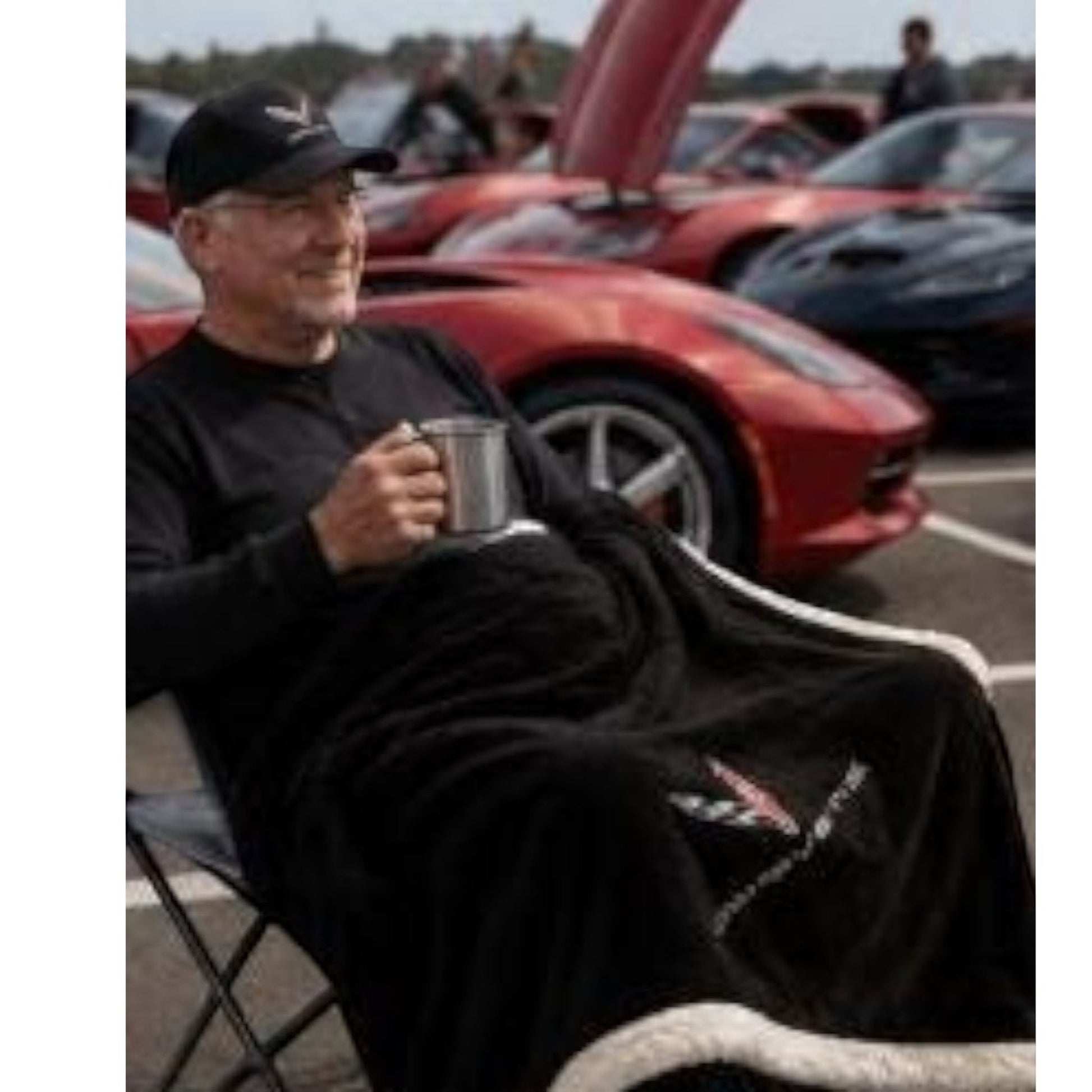 T-Top Vibes black Corvette plush sherpa throw blanket with embroidered logo, used by a man at a car show.