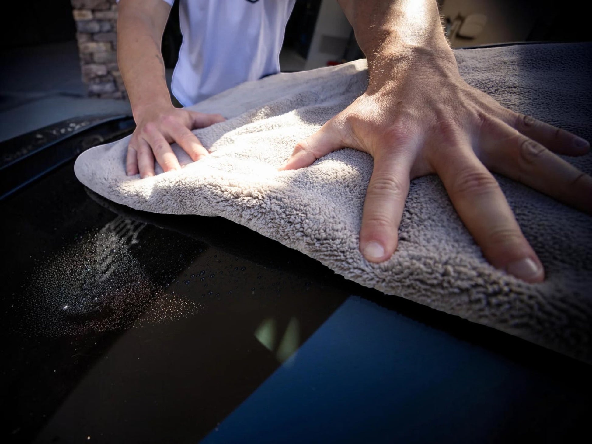 T-Top Vibes gray plush microfiber car drying towel being used to gently dry a vehicle hood